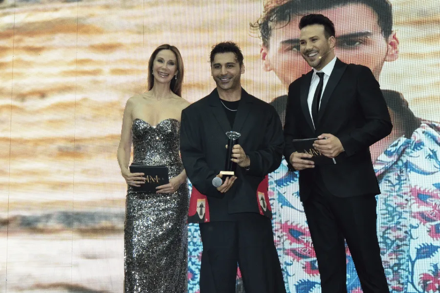 Three people on stage during an award presentation